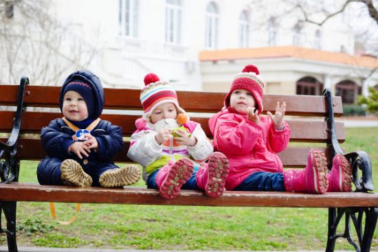 baby girl 11 months in warm clothes sits on snow outdoor in winter