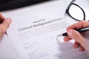 Person Hand Filling Criminal Background Check Application Form